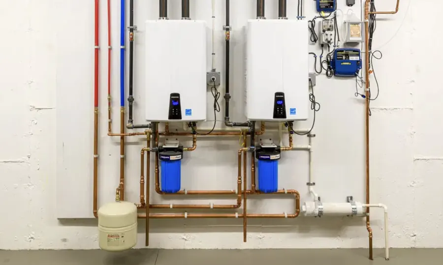 Two tankless water heaters mounted side by side with filters, valves and an expansion tank &mdash; Foothills Water Heaters