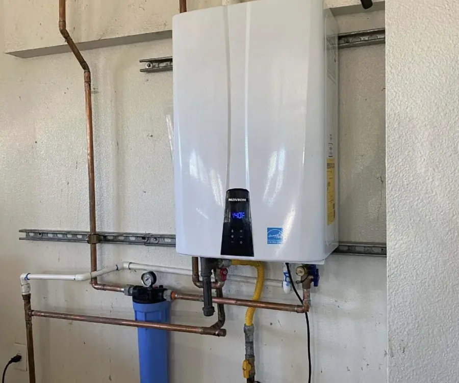 Wall-mounted tankless gas water heater with copper piping and a blue sediment filter &mdash; Foothills Water Heaters